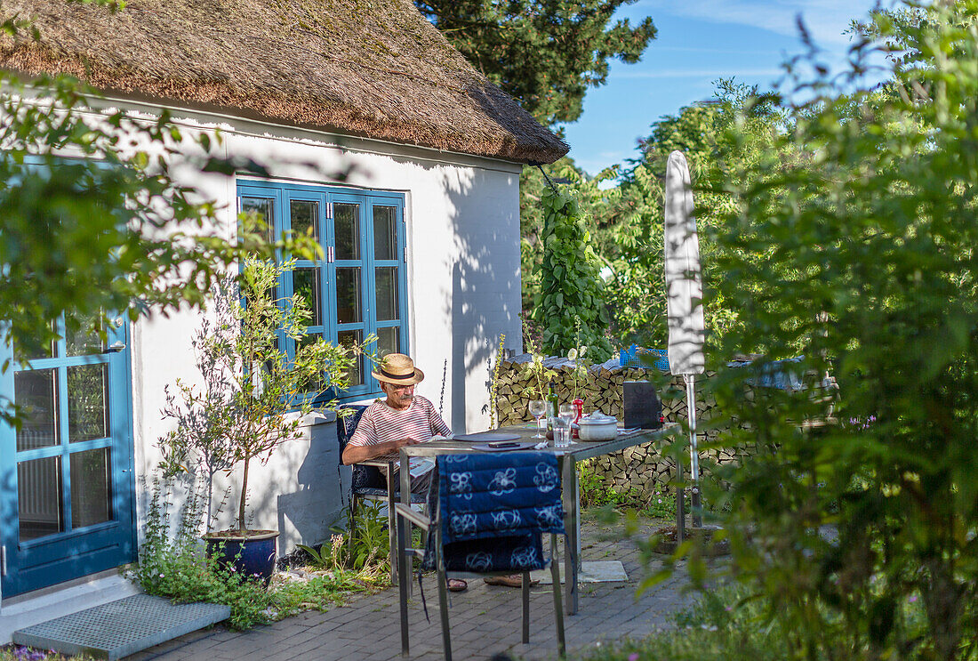 Älterer Mann beim Entspannen vor dem Haus