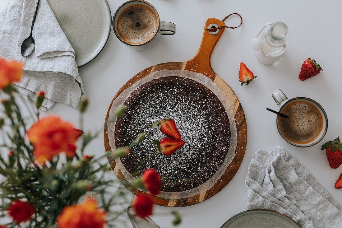 Freshly baked chocolate cake with strawberries on table\n