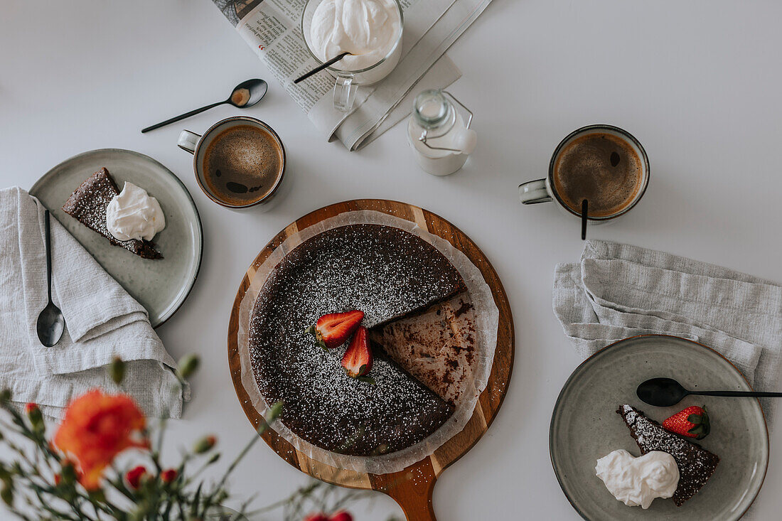 Freshly baked chocolate cake with strawberries on cream on table\n