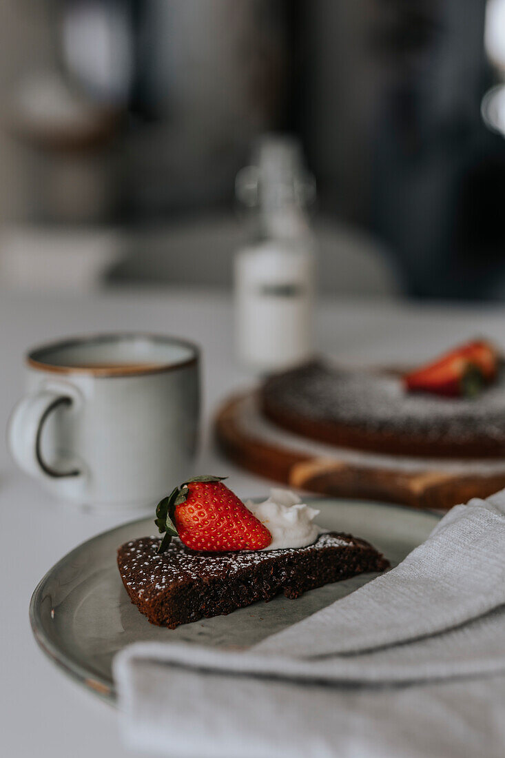 Freshly baked chocolate cake with strawberries and cream on table\n