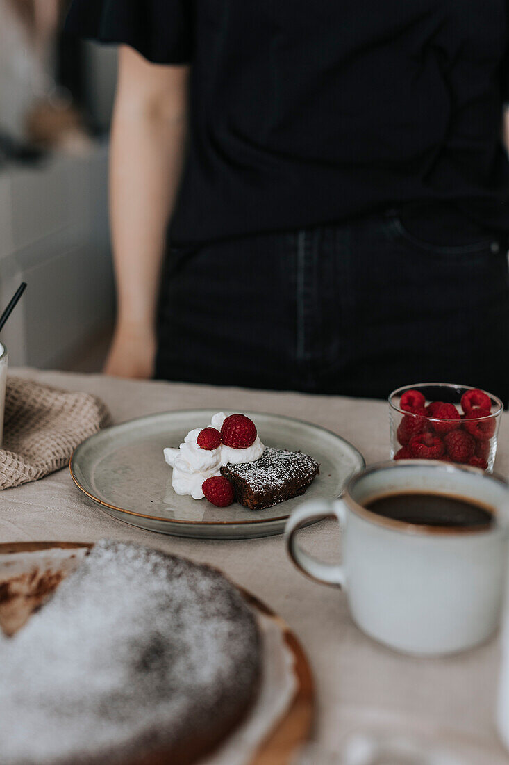 Portion Schokoladenkuchen mit Sahne und Himbeeren auf dem Teller