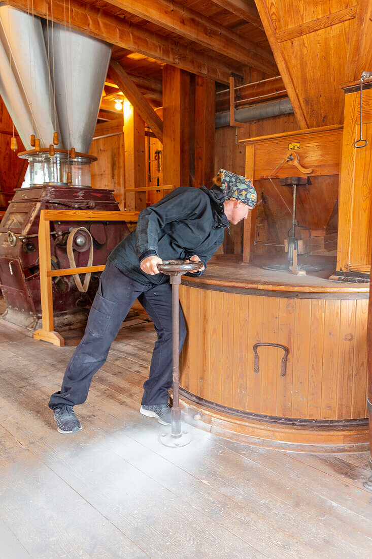 Woman in flour mill checking working machinery\n