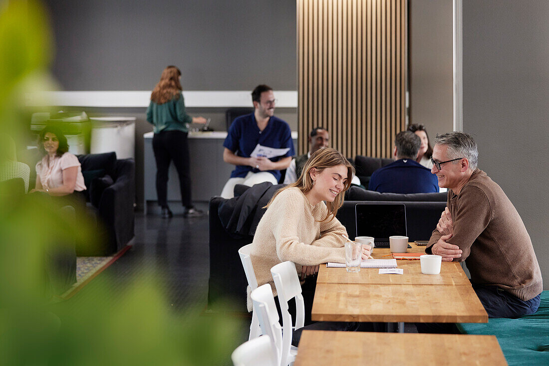 Two professionals working together in office cafeteria\n