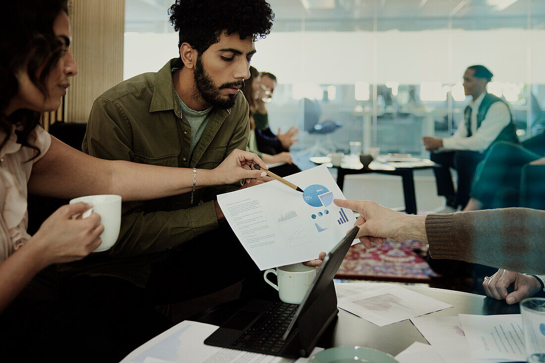 Group of business people analyzing charts during meeting in lobby\n