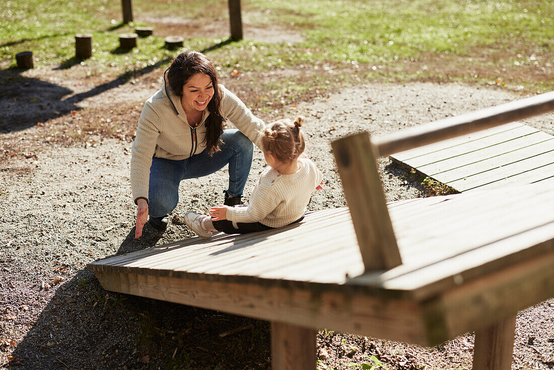 Mother looking at daughter playing at playground\n