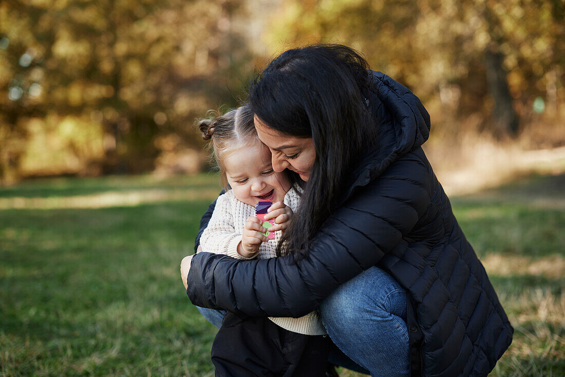 Glückliche Mutter umarmt Tochter im Park