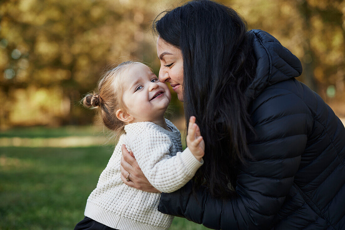 Happy mother hugging daughter in park\n