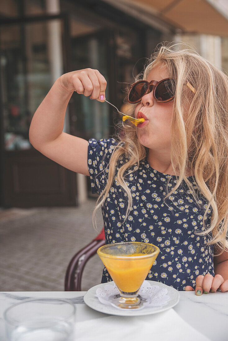 Girl eating dessert in outdoor cafe\n