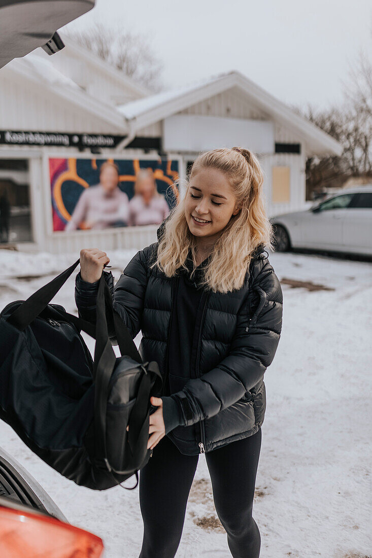 Junge Frau packt Tasche im Auto nach dem Training im Fitnessstudio