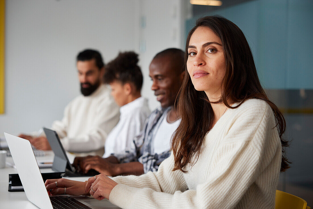 Smiling woman sitting during business meeting and looking at camera\n