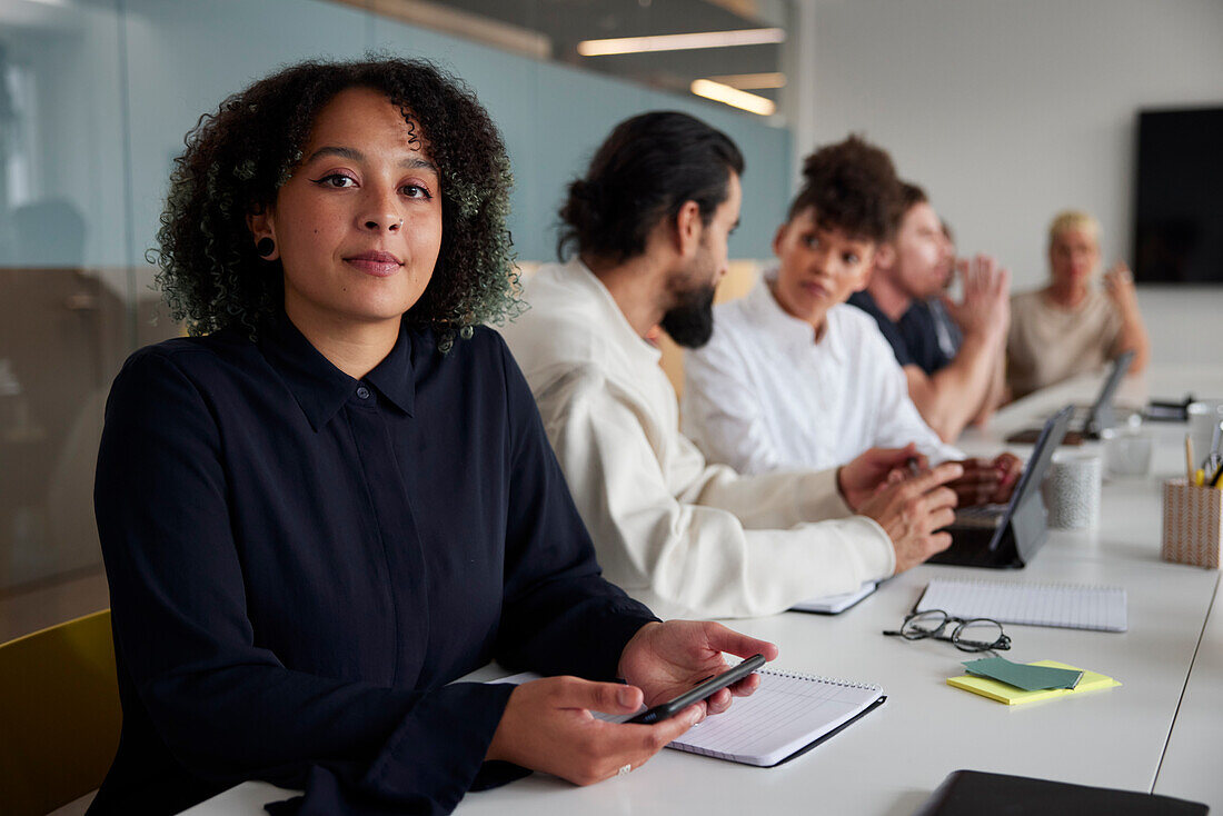 Woman sitting during business meeting and looking at camera\n