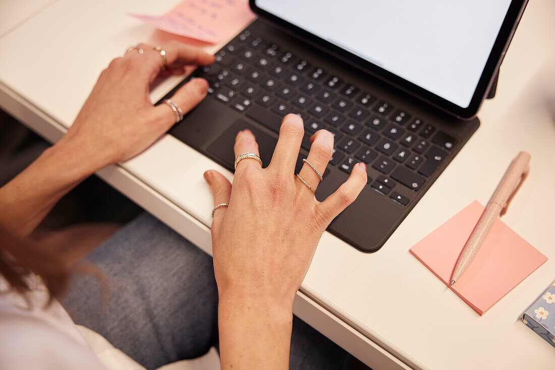Blick von oben auf die Hände einer Frau, die einen Laptop benutzt