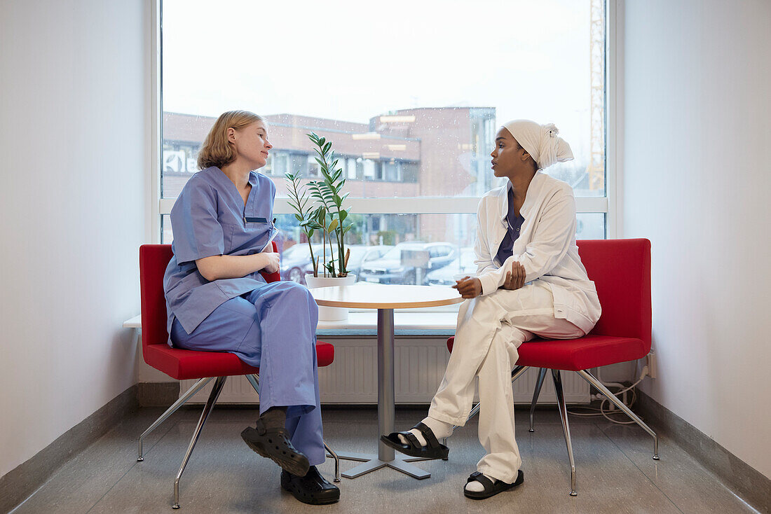 Female doctors sitting in hospital and talking to each other\n