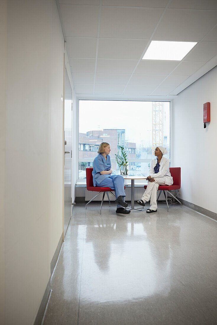 Female doctors sitting in hospital and talking to each other\n