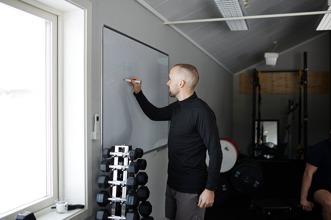 Man writing on whiteboard in gym\n