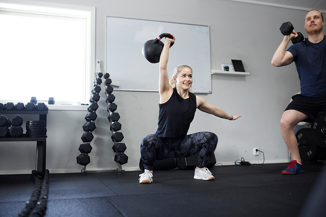 Two people lifting weights in gym\n