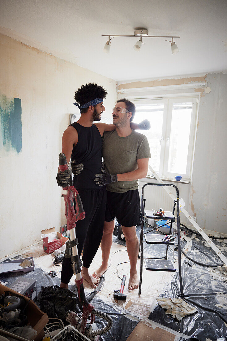 Lächelndes männliches homosexuelles Paar schaut sich bei der Wohnungsrenovierung an