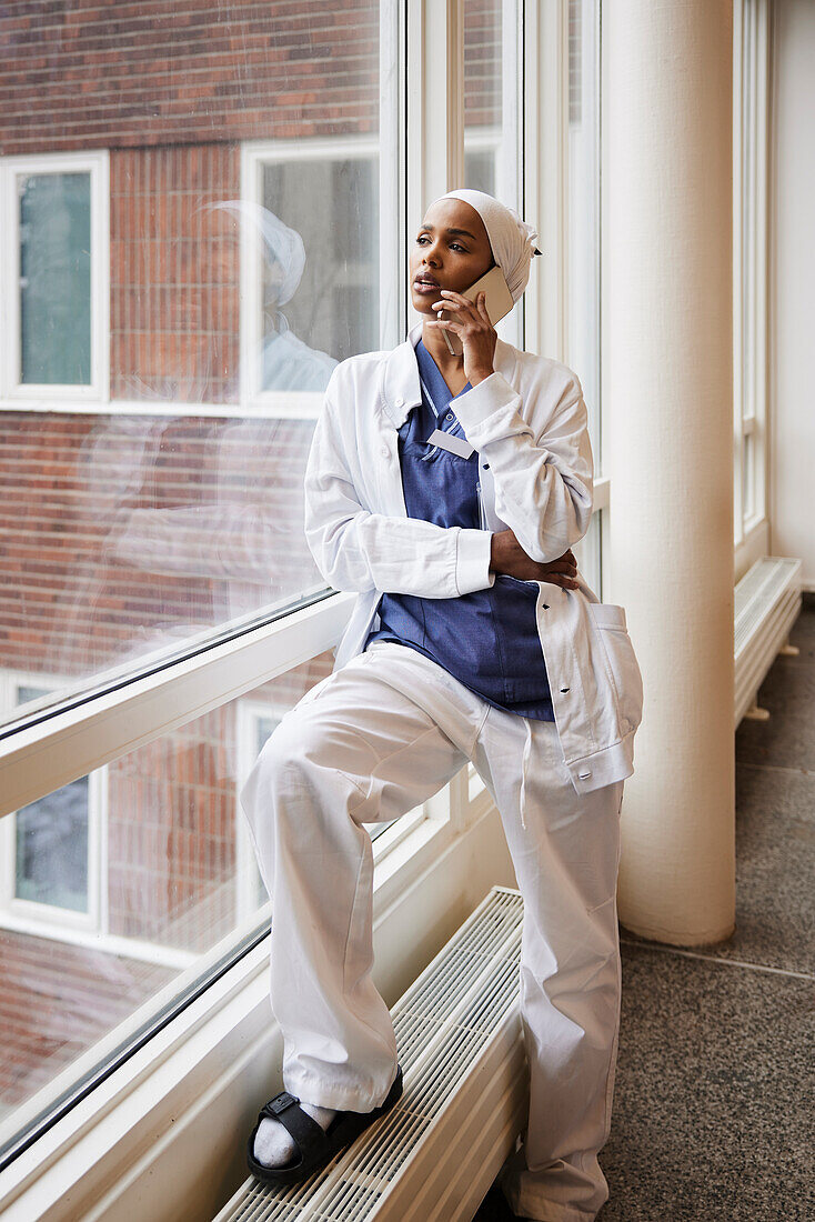 Young female doctor talking on phone at work\n