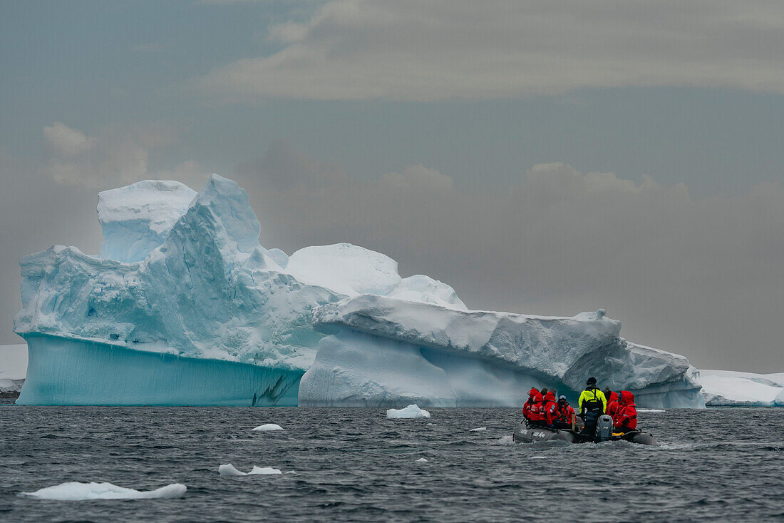 Tourists in an inflatable boat exploring Pleneau Island, Antarctica.\n