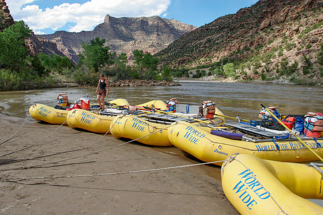 A female river guide walking on white water rafts tied up on shore in Desolation Canyon, Utah.\n