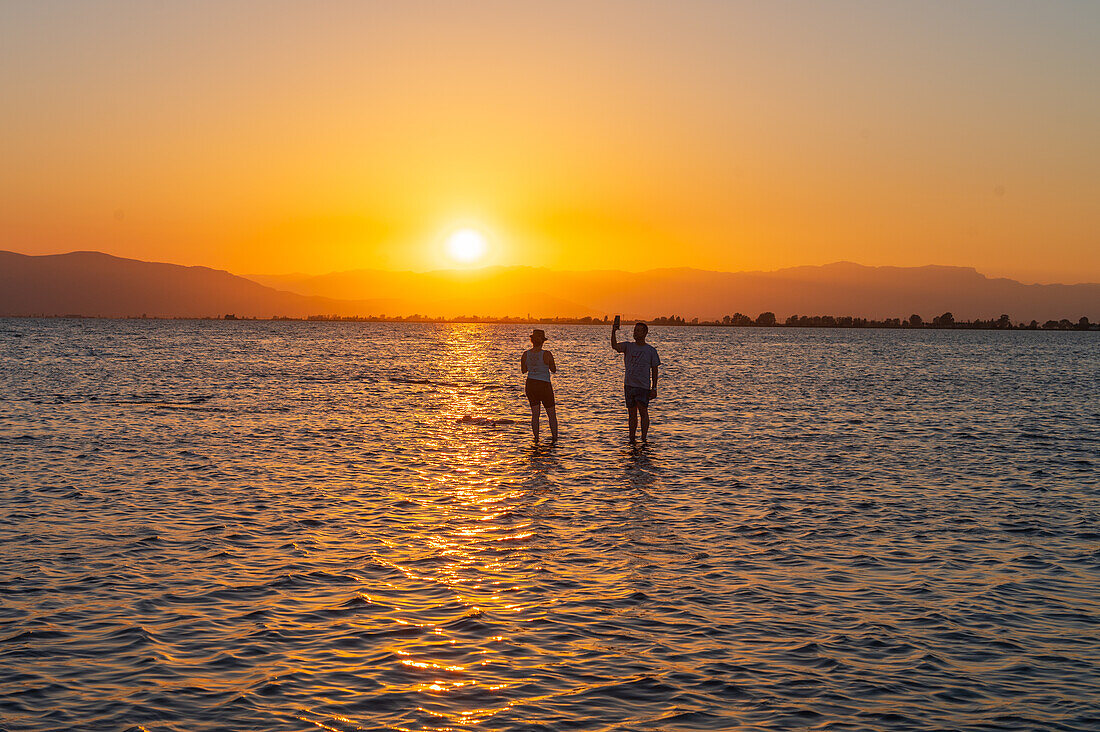 Menschen genießen den Sonnenuntergang am Strand von Trabucador, Ebro-Delta, Tarragona, Spanien