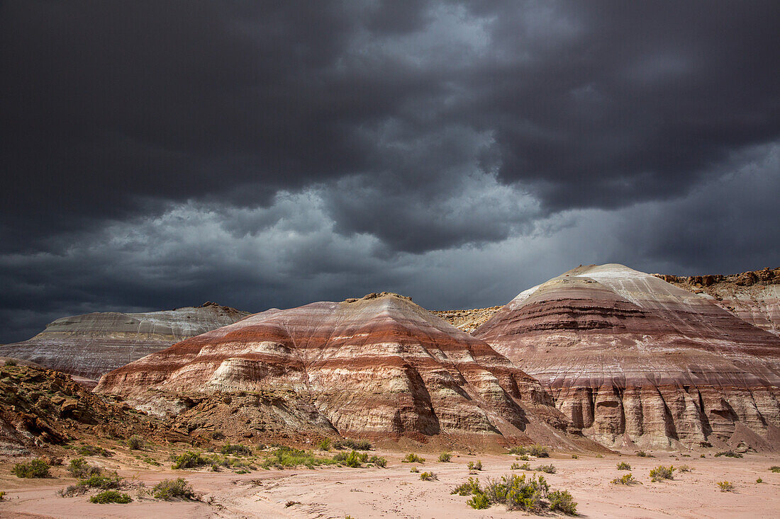 Sturmwolken über erodierten Sandsteinformationen und bunten Bentonit-Tonhügeln in der Caineville-Wüste bei Hanksville, Utah.