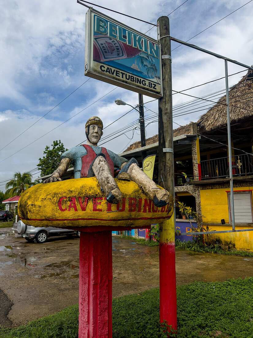 A cement statue of a person in a tube in front of a cave tubing tour company in the Cayo District of Belize.\n