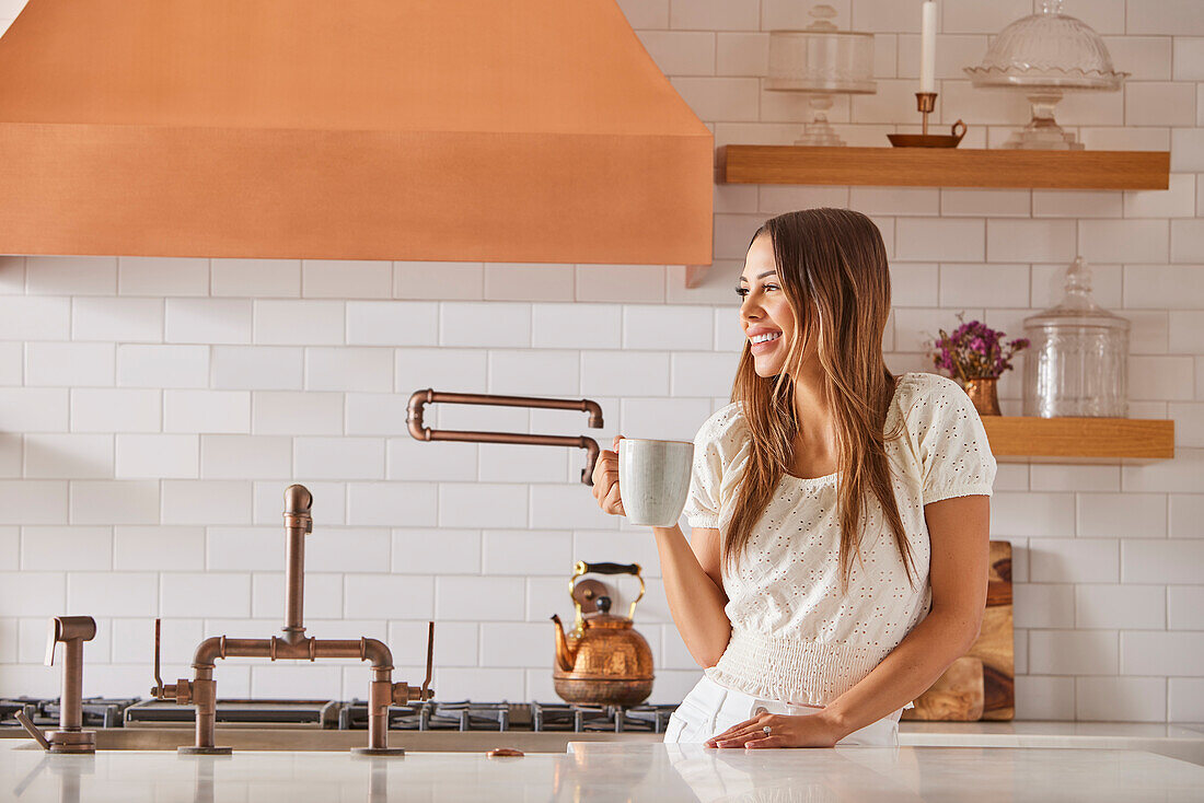 Smiling woman holding mug in kitchen\n