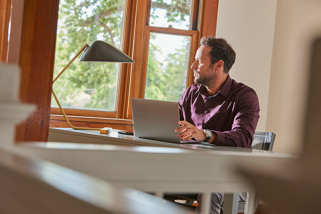 Man using laptop at table at home\n