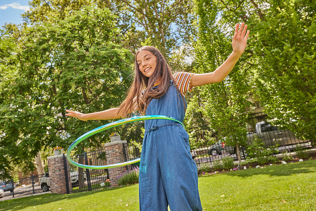 Lächelndes Mädchen (12-13) spielt mit Hula-Hoop-Reifen im Park