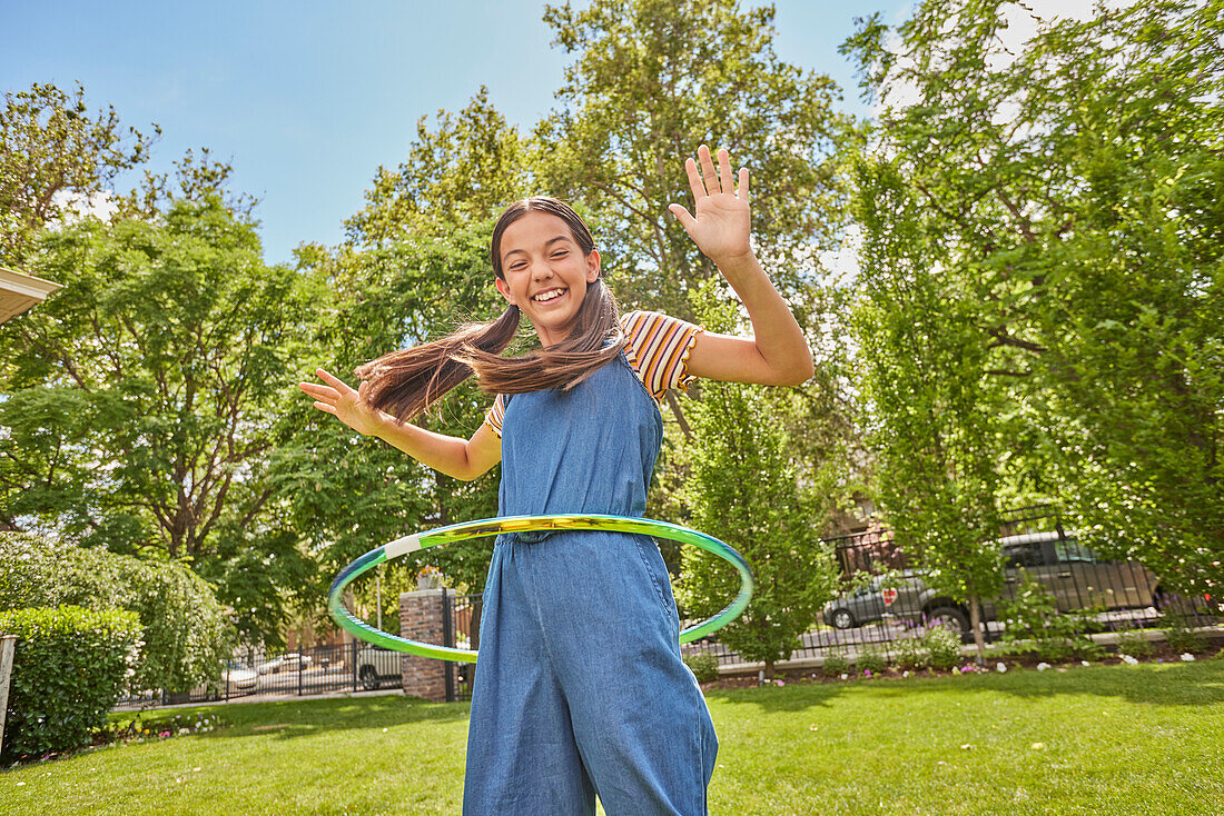 Lächelndes Mädchen (12-13) spielt mit Hula-Hoop-Reifen im Park