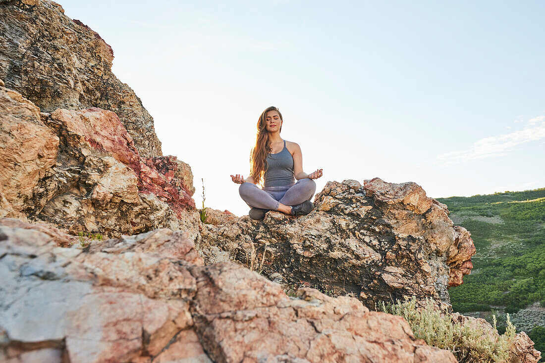 Mid adult woman meditating in mountains\n