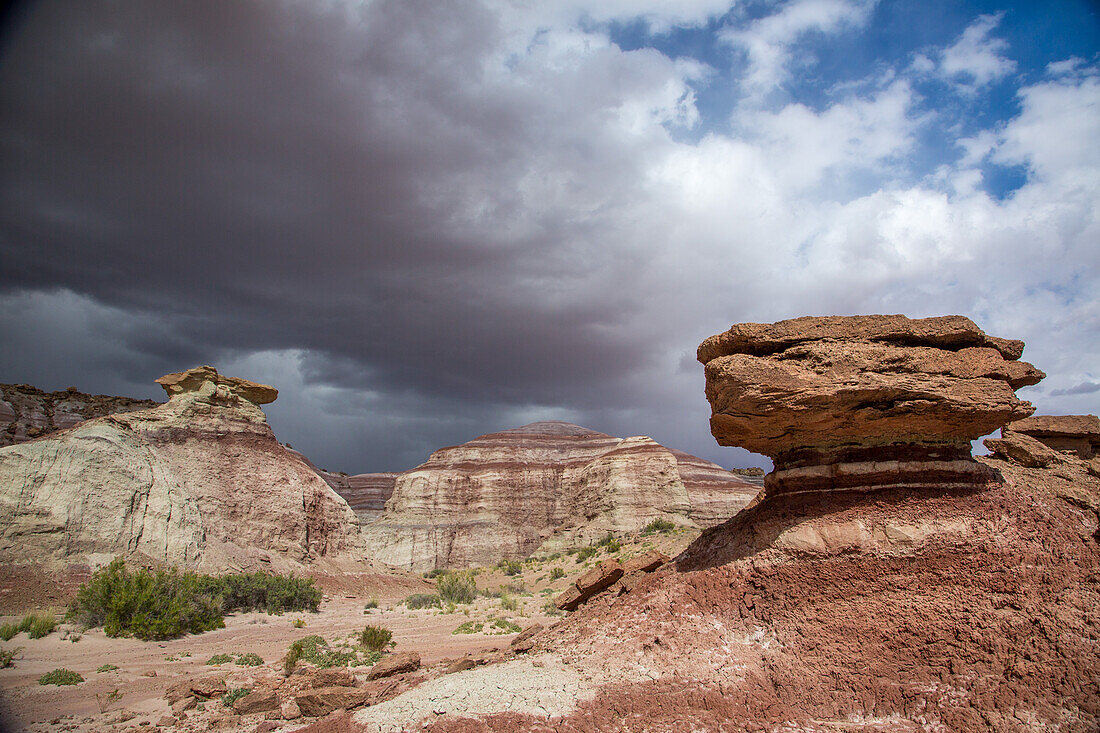 Storm clouds over eroded sandstone formations & colorful bentonite clay hills in the Caineville Desert near Hanksville, Utah.\n