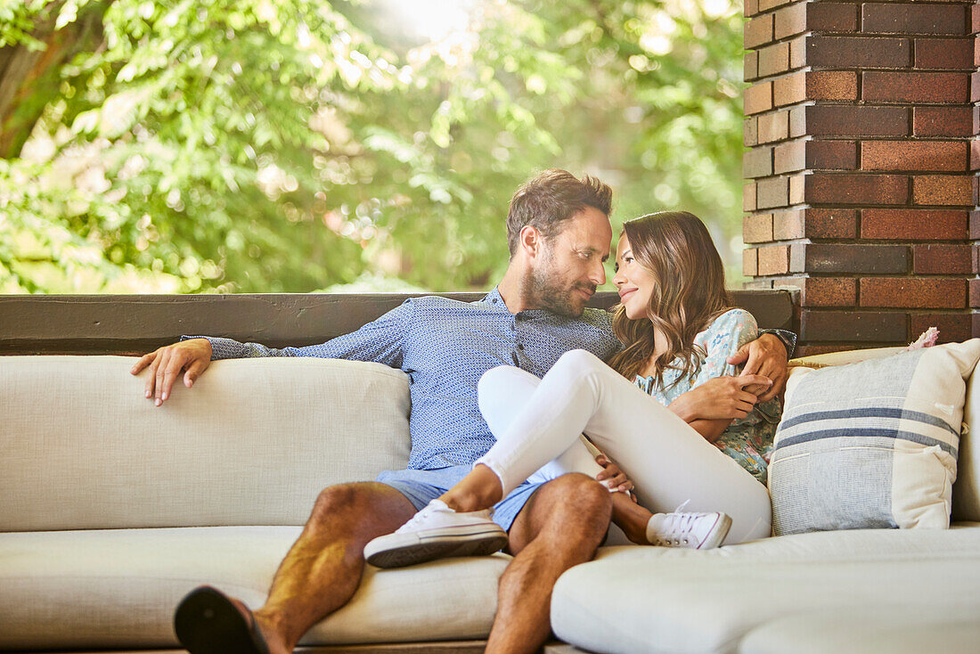 Mid adult couple relaxing on sofa on patio\n