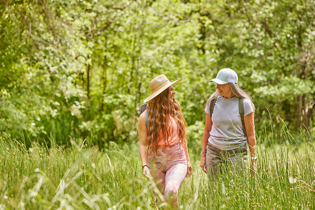 Mother and adult daughter hiking in forest\n