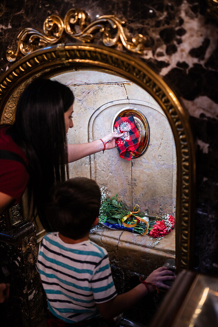 Worshipers kissing the pillar inside the Cathedral-Basilica of Our Lady of the Pillar during The Offering of Flowers to the Virgen del Pilar, the most important and popular event of the Fiestas del Pilar held on Hispanic Day, Zaragoza, Spain\n