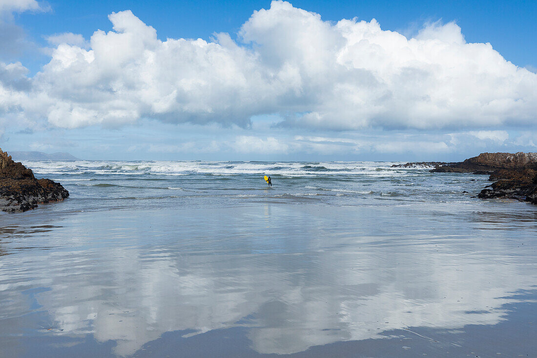 South Africa, Hermanus, Distant view of boy (10-11) bodyboarding in Atlantic Ocean in Kammabaai Beach\n