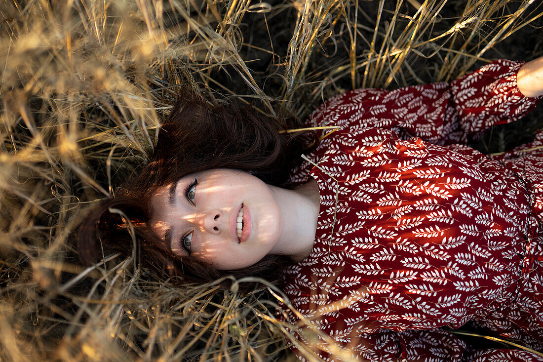 Directly above view of woman lying on cereal plants in field\n