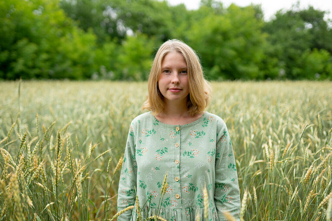 Young woman standing in wheat field in summer \n