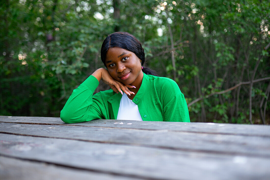 Smiling woman sitting at picnic table \n