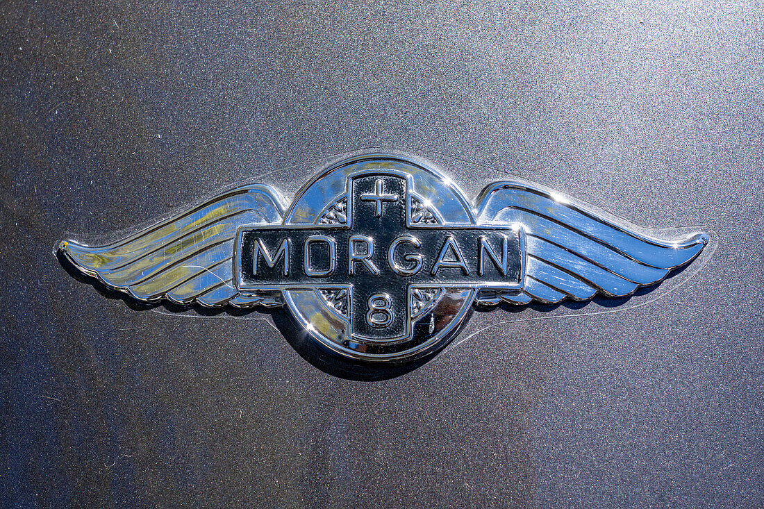 A the badge on the hood of a 1991 Morgan Plus 8 sports car in a car show in Moab, Utah.\n