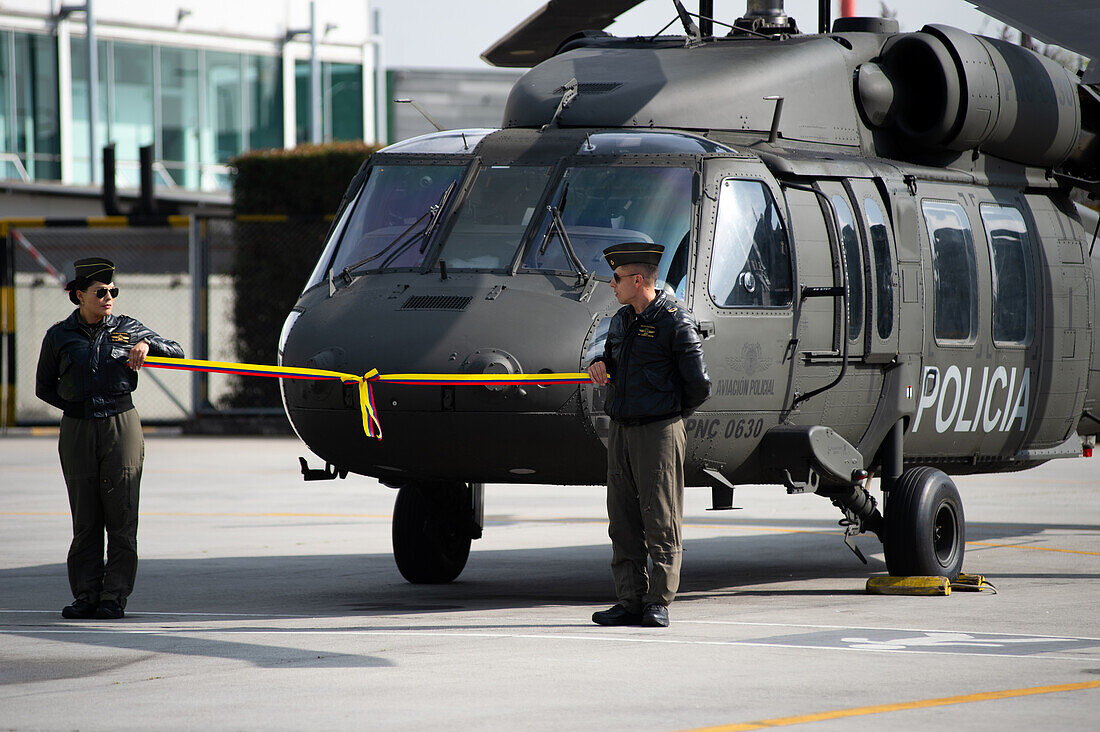 Two pilots hold a ribbon of the Colombian flag in front of a UH60 Black Hawk during an event at the CATAM - Airbase in Bogota, where the United States of America embassy in Colombia gave 3 Lockheed Martin UH60 Black Hawks to improve the antinarcotics operations, on September 27, 2023.\n