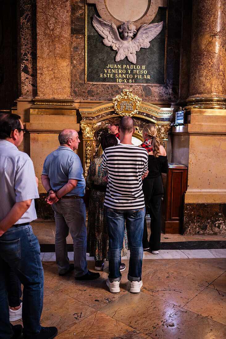 Eine Reihe von Gläubigen, die darauf warten, die Säule in der Kathedrale-Basilika Unserer Lieben Frau von der Säule zu küssen, während der Blumenspende für die Virgen del Pilar, der wichtigsten und beliebtesten Veranstaltung der Fiestas del Pilar, die am Tag der Spanier stattfindet, Zaragoza, Spanien