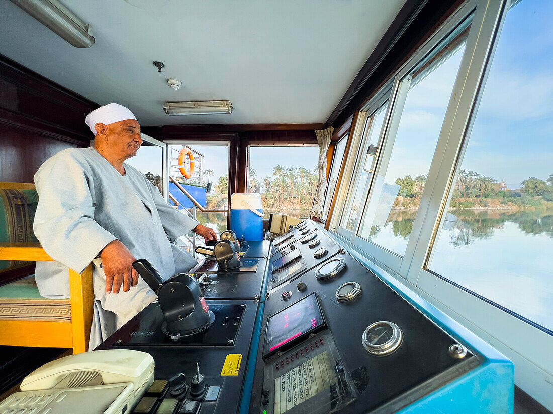 Egyptian Captain of the Oberoi Philae at the helm on the Nile River, Dendera, Egypt, North Africa, Africa\n
