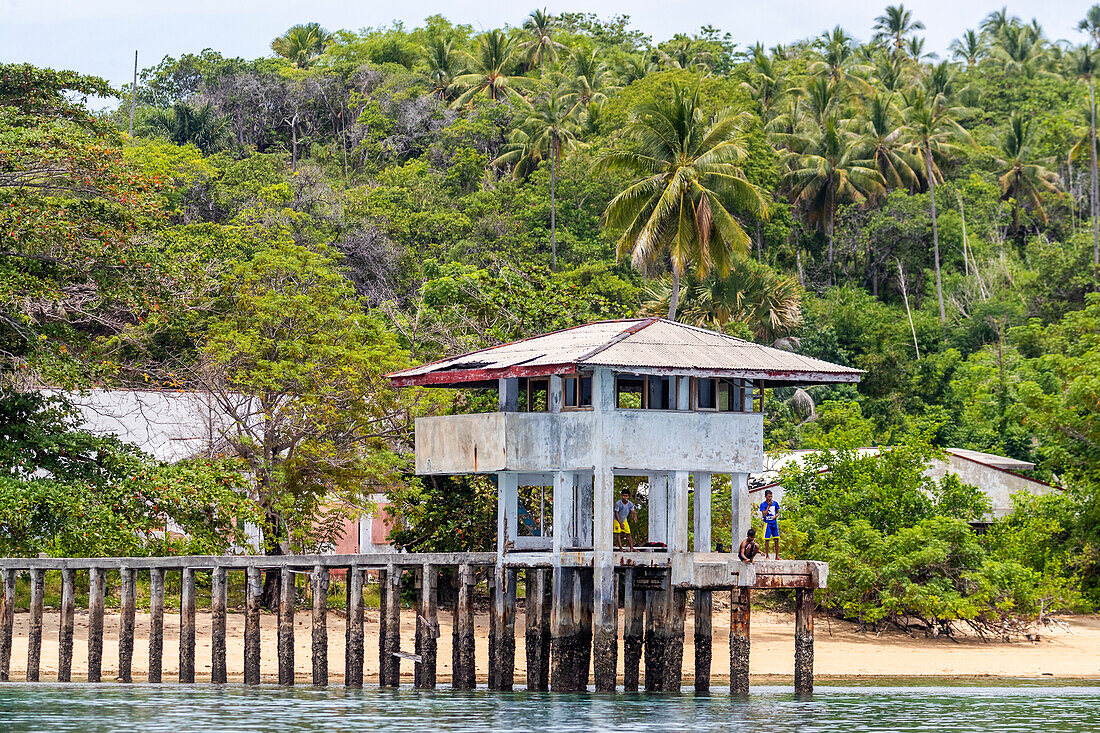 Young men fishing from a local building on Bangka Island, off the northeastern tip of Sulawesi, Indonesia, Southeast Asia, Asia\n