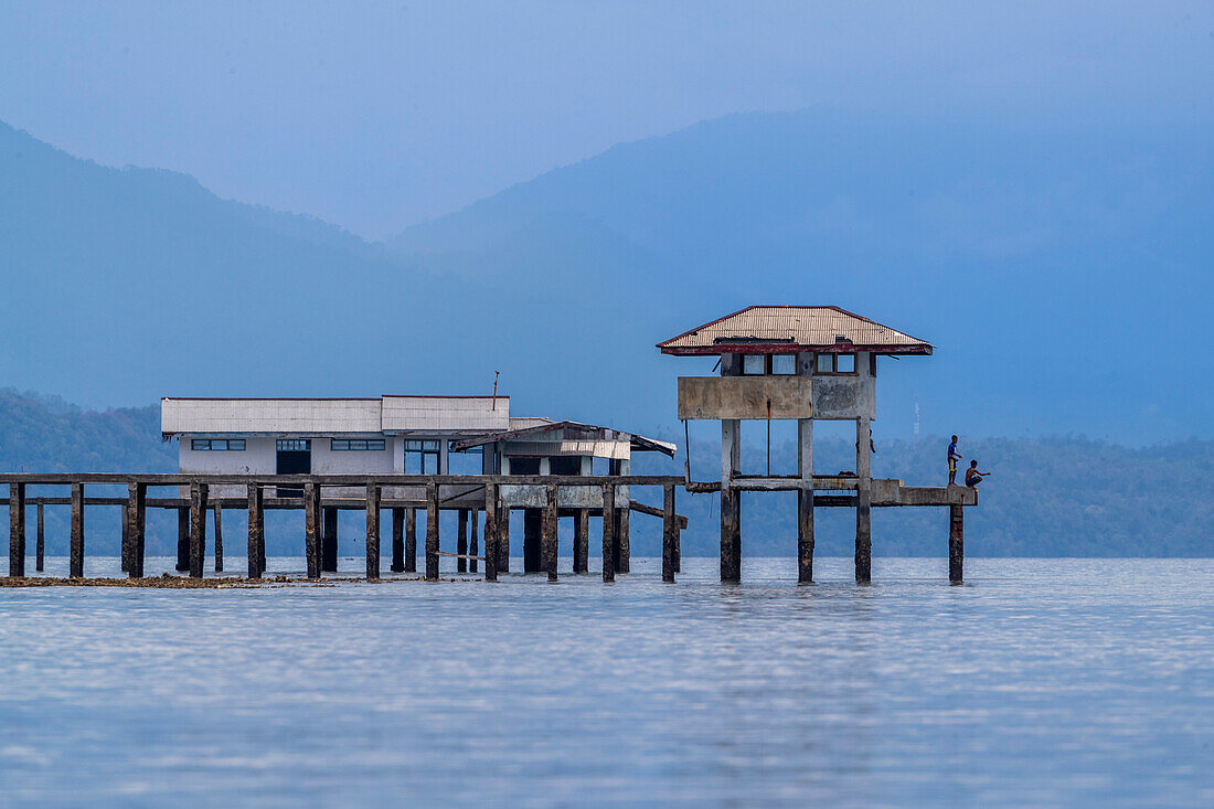 Junge Männer fischen von einem Gebäude aus auf der Insel Bangka, vor der nordöstlichen Spitze von Sulawesi, Indonesien, Südostasien, Asien