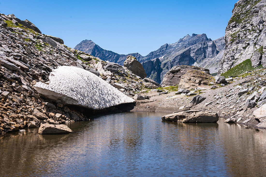 Reste eines Schneefeldes in den Alpen, das auf einem Alpenpass zu einem See schmilzt, die Alpen, Piemont, Norditalien, Europa