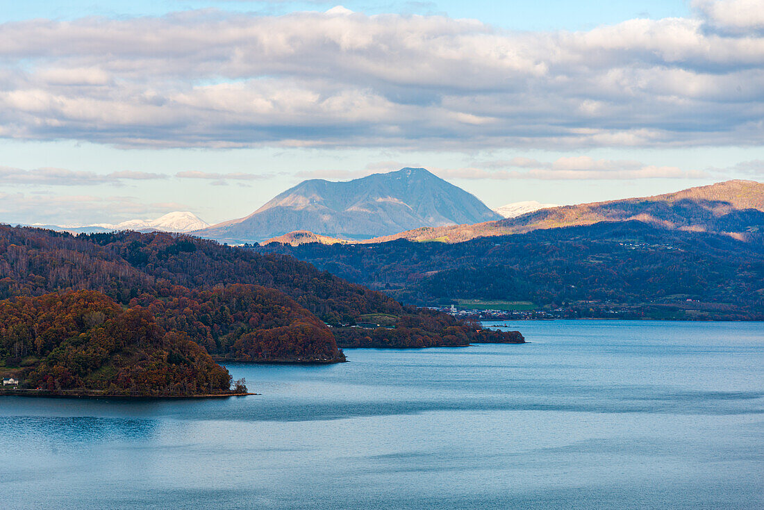 View over the forest slope of Lake Toya in the evening with volcano in the distance, Abuta, Hokkaido, Japan, Asia\n