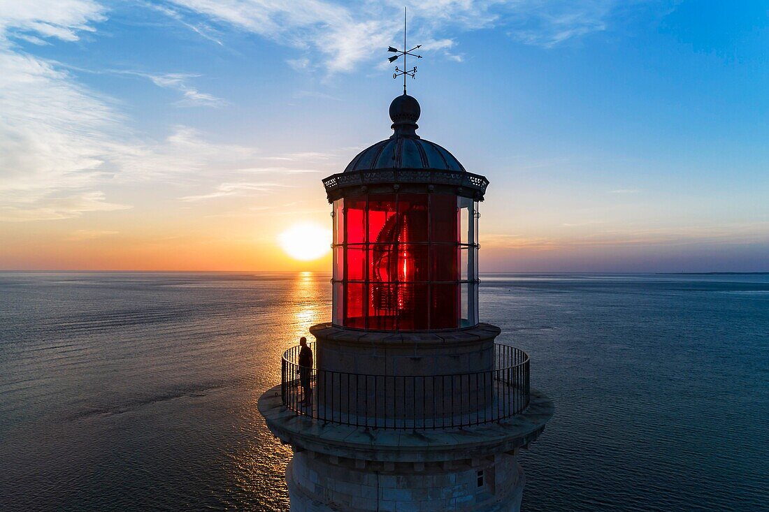France, Gironde, Verdon-sur-Mer, rocky plateau of Cordouan, lighthouse of Cordouan, listed as World Heritage by UNESCO, lighthouse keeper at the lantern at sunset (aerial view)\n