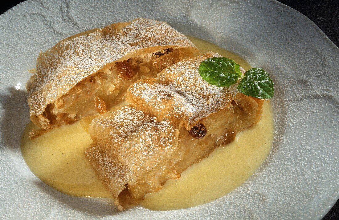 Zwei Stück Apfelstrudel mit Vanillesauce auf Teller